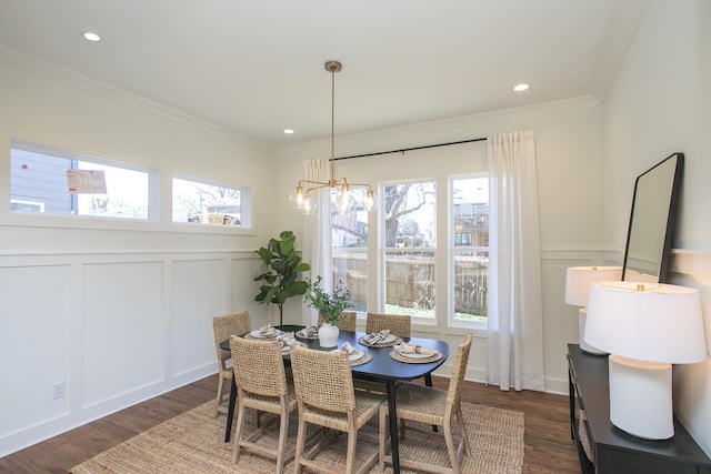 dining area with ornamental molding, dark hardwood / wood-style floors, and an inviting chandelier