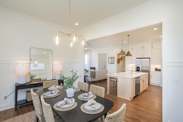 dining space with sink, hardwood / wood-style flooring, and ornamental molding