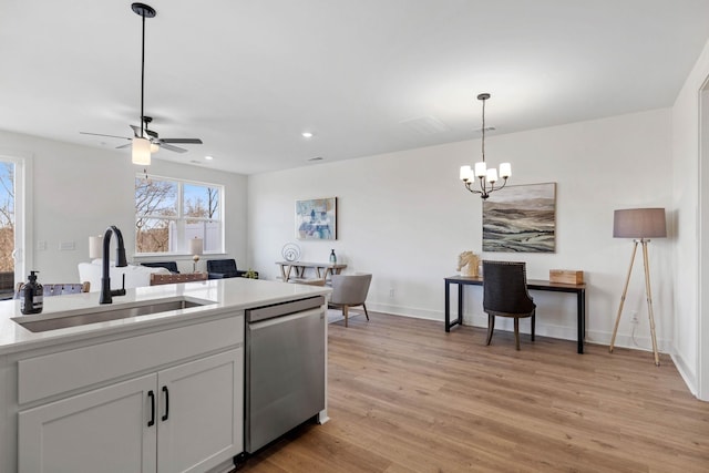 kitchen featuring sink, light hardwood / wood-style flooring, white cabinetry, decorative light fixtures, and stainless steel dishwasher