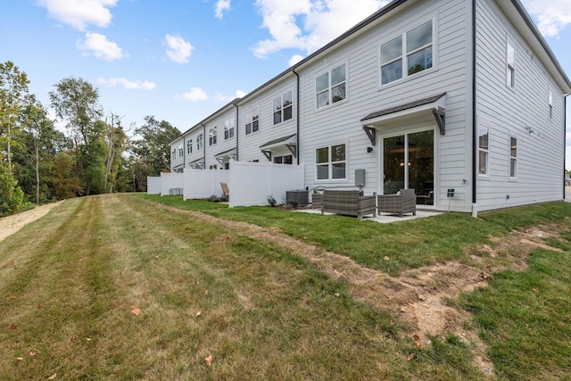 back of house featuring an outdoor living space, cooling unit, a patio area, and a lawn