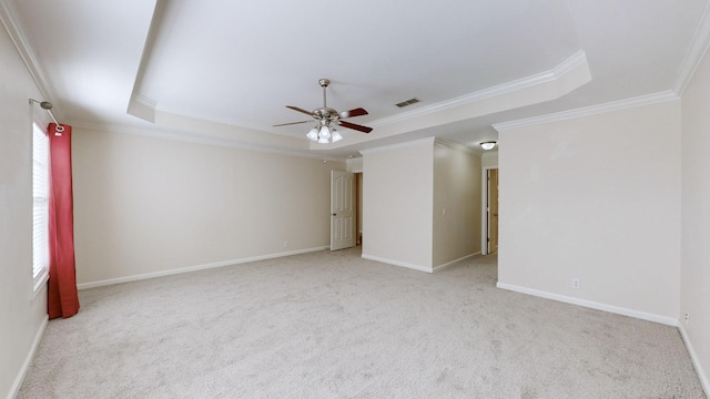 unfurnished room featuring a raised ceiling, ornamental molding, light colored carpet, and ceiling fan