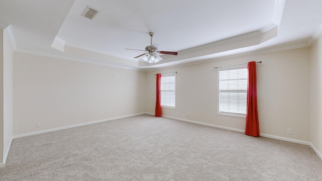 carpeted spare room with ornamental molding, ceiling fan, and a tray ceiling