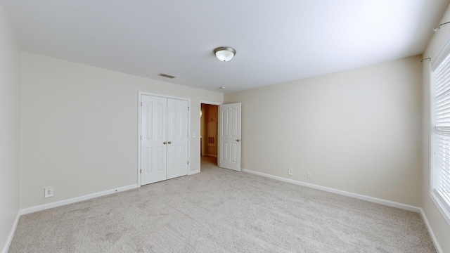 unfurnished bedroom featuring multiple windows, light colored carpet, and a closet