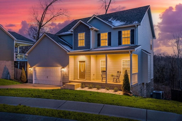 view of front of property featuring a porch, a garage, a yard, and central air condition unit