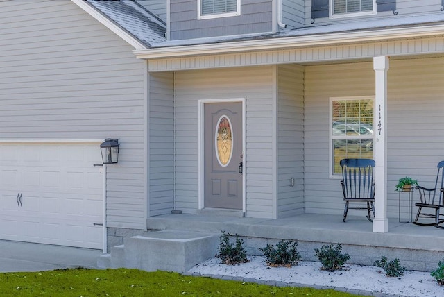 view of exterior entry with a garage and covered porch