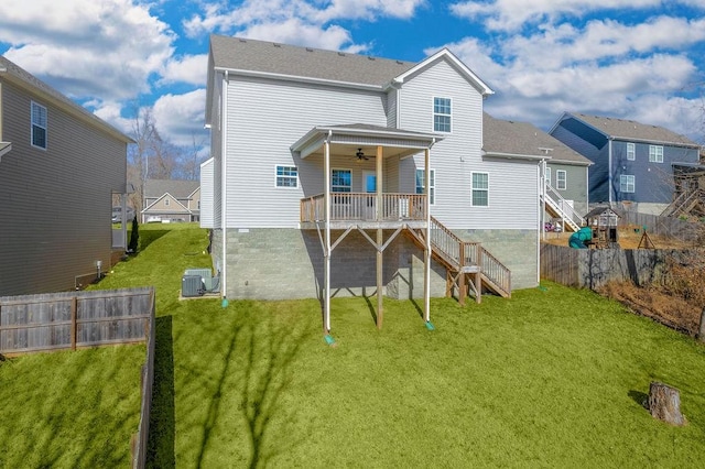 rear view of house with central AC, ceiling fan, and a lawn