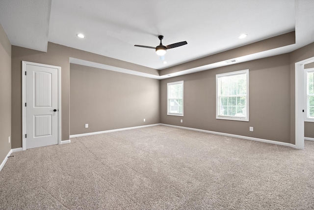 unfurnished room with a tray ceiling, ceiling fan, and carpet