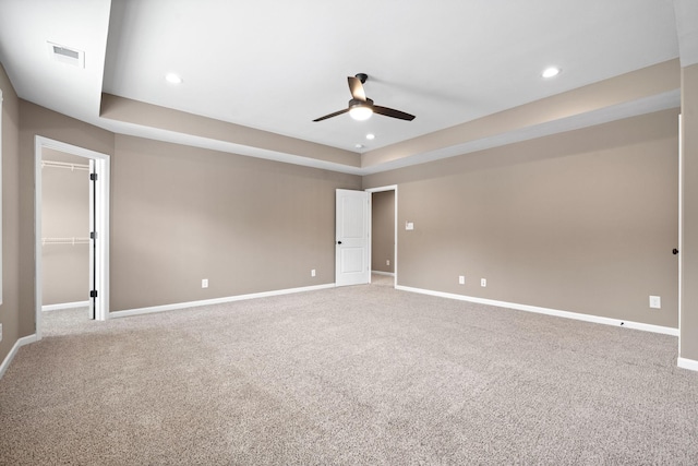 carpeted spare room featuring ceiling fan and a tray ceiling