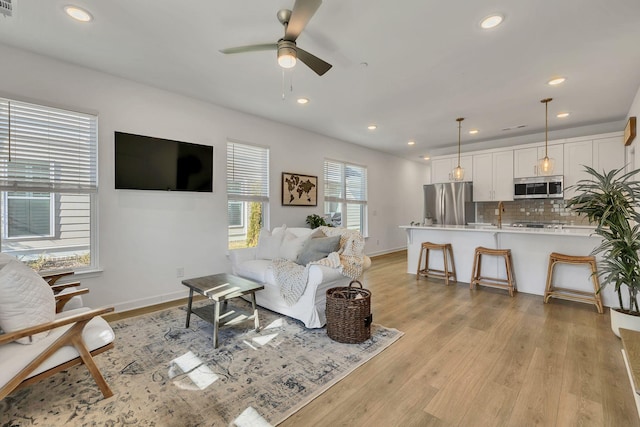 living room with light hardwood / wood-style floors and ceiling fan