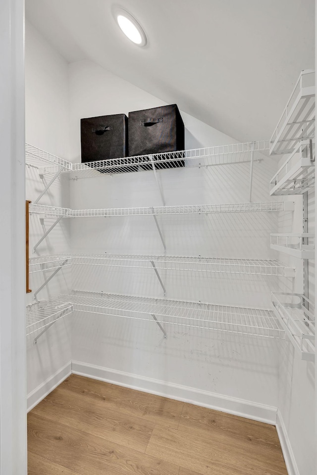 walk in closet with lofted ceiling and wood-type flooring