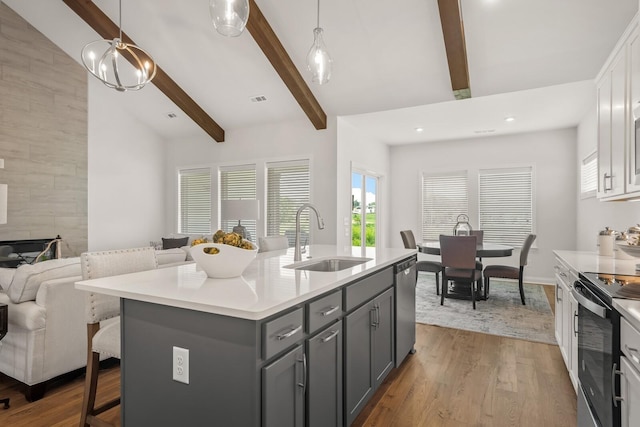 kitchen featuring pendant lighting, sink, white cabinets, a kitchen island with sink, and electric stove