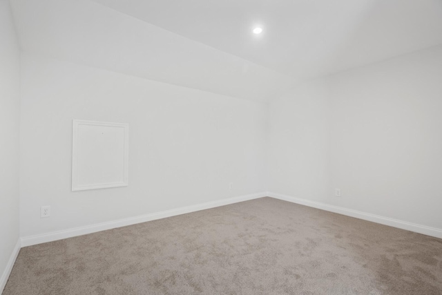 spare room with carpet floors and vaulted ceiling