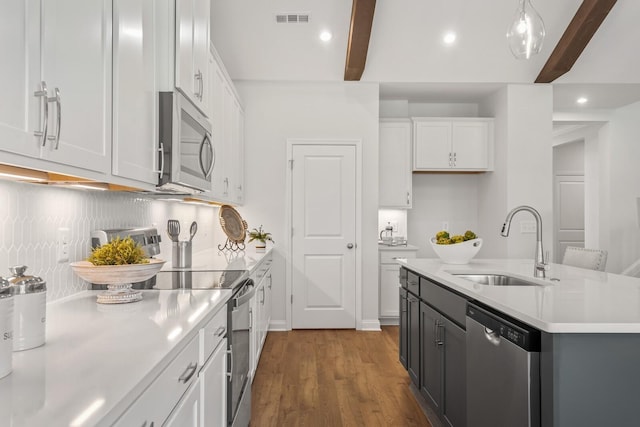 kitchen featuring pendant lighting, white cabinetry, sink, stainless steel appliances, and beam ceiling