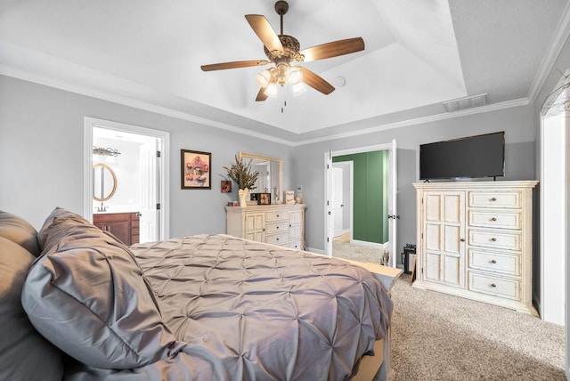 carpeted bedroom featuring ceiling fan, ornamental molding, a tray ceiling, and ensuite bath