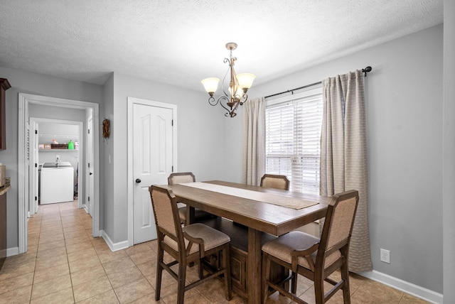 dining room featuring a notable chandelier, washer / dryer, a textured ceiling, and light tile patterned flooring