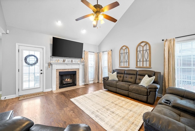 living room featuring a tiled fireplace, dark hardwood / wood-style flooring, ceiling fan, and high vaulted ceiling