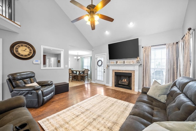 living room with hardwood / wood-style flooring, a fireplace, ceiling fan with notable chandelier, and high vaulted ceiling