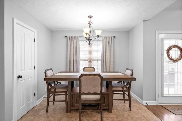 dining area with a chandelier, a textured ceiling, and light tile patterned flooring