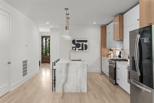 kitchen featuring pendant lighting, sink, white cabinets, backsplash, and stainless steel appliances