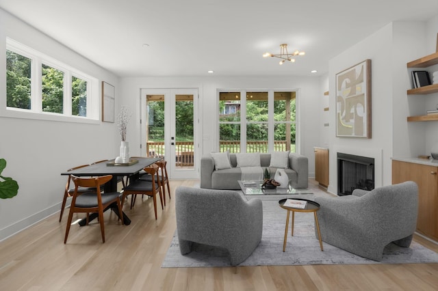 living room with a notable chandelier, light hardwood / wood-style floors, and french doors