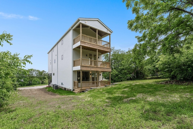 rear view of property featuring central AC unit, a yard, and a balcony