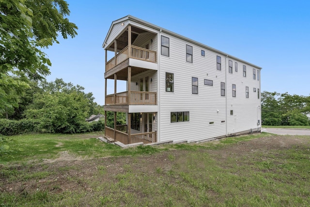 back of house with a balcony and a lawn