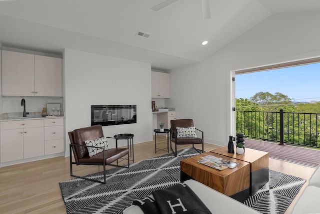 interior space with sink, plenty of natural light, vaulted ceiling, and light wood-type flooring