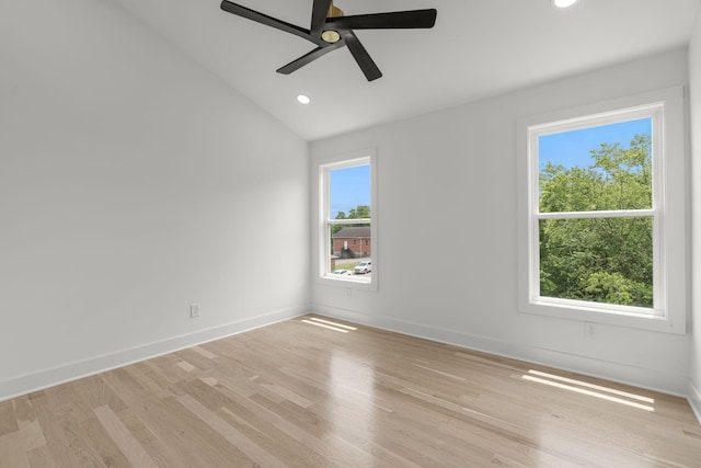 spare room featuring lofted ceiling, plenty of natural light, and light hardwood / wood-style floors