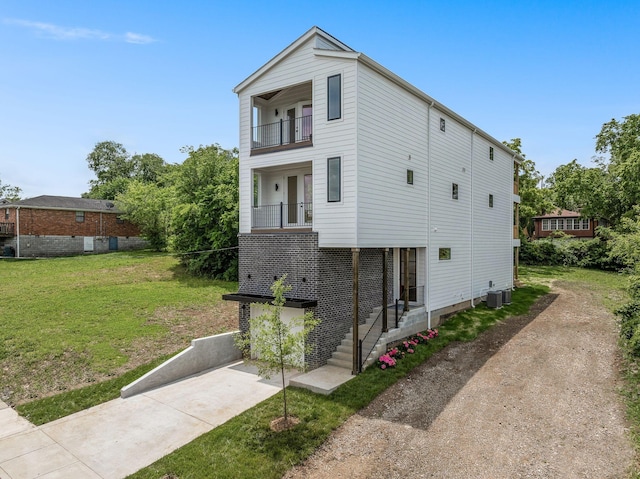 view of front facade with a garage, a balcony, central air condition unit, and a front lawn