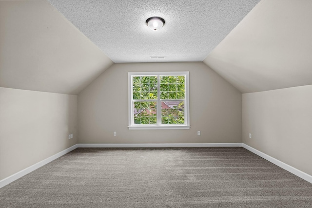 bonus room featuring vaulted ceiling, a textured ceiling, and carpet flooring