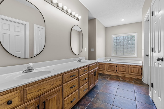 bathroom featuring vanity, a bath, and a textured ceiling