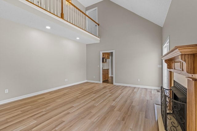 unfurnished living room with high vaulted ceiling and light hardwood / wood-style flooring