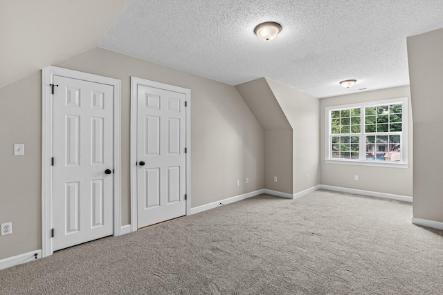 bonus room featuring vaulted ceiling, carpet floors, and a textured ceiling