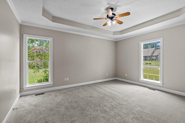 carpeted spare room featuring ornamental molding, a textured ceiling, ceiling fan, and a tray ceiling