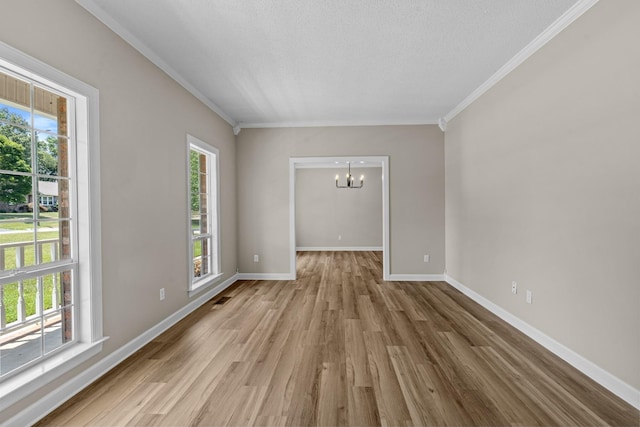 empty room featuring ornamental molding, light wood-type flooring, a textured ceiling, and an inviting chandelier