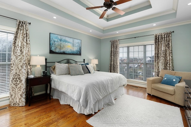 bedroom with ceiling fan, ornamental molding, a tray ceiling, and hardwood / wood-style floors