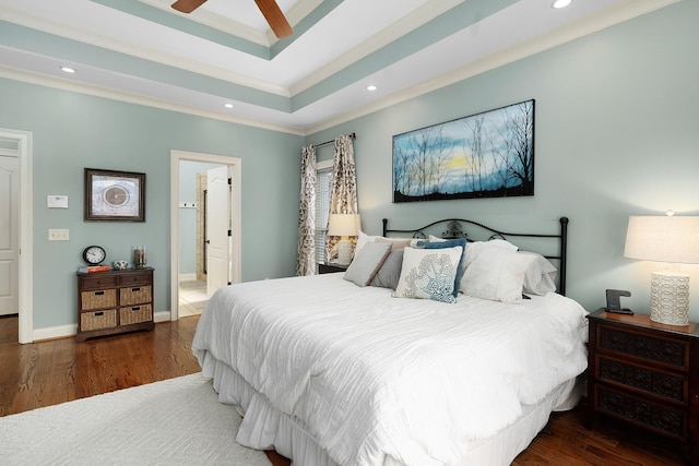 bedroom featuring ensuite bathroom, ornamental molding, dark hardwood / wood-style flooring, a tray ceiling, and ceiling fan