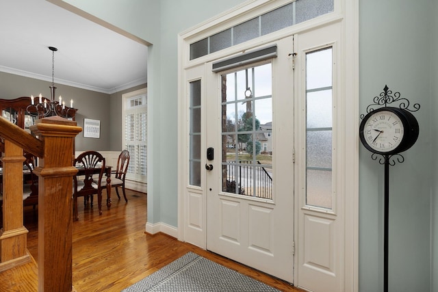 entryway with a notable chandelier, crown molding, and hardwood / wood-style flooring