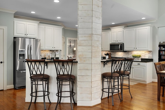 kitchen featuring ornamental molding, stainless steel appliances, a breakfast bar, and white cabinets