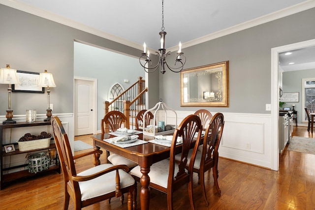 dining space with crown molding, wood-type flooring, and a chandelier