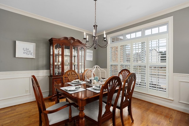 dining room with wood-type flooring, ornamental molding, and a chandelier