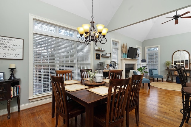 dining space with lofted ceiling, ceiling fan with notable chandelier, and wood-type flooring