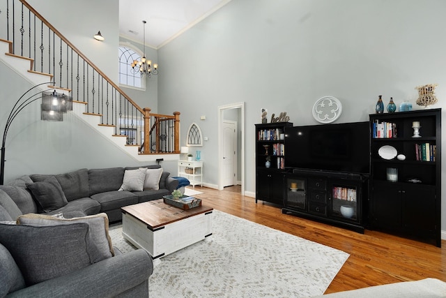 living room featuring an inviting chandelier, ornamental molding, hardwood / wood-style floors, and a high ceiling