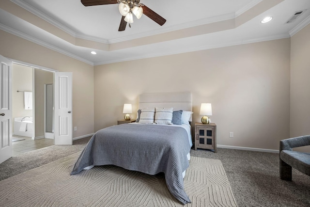 bedroom with ornamental molding, connected bathroom, ceiling fan, and a tray ceiling