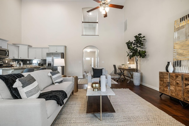 living room with ceiling fan, a towering ceiling, dark hardwood / wood-style floors, and sink