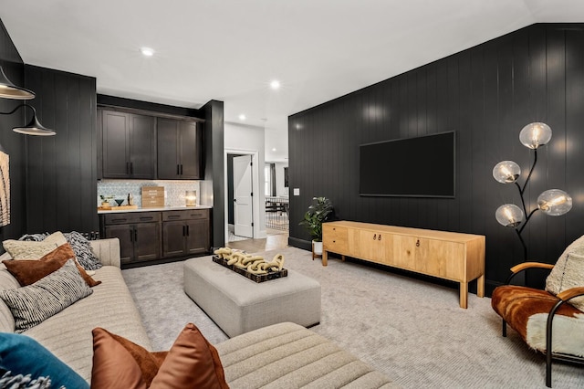 carpeted living room featuring wood walls