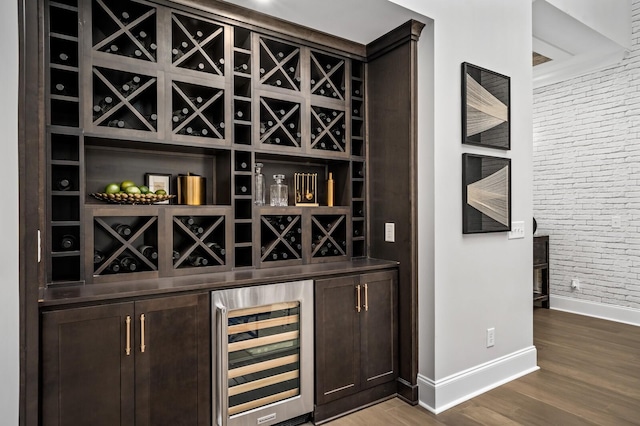 bar featuring hardwood / wood-style flooring, brick wall, dark brown cabinets, and wine cooler