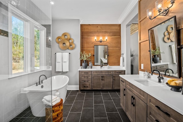 bathroom featuring tile patterned floors, a bathing tub, vanity, and tile walls