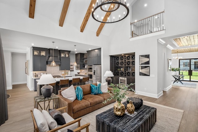 living room featuring an inviting chandelier, beam ceiling, high vaulted ceiling, light hardwood / wood-style floors, and beverage cooler