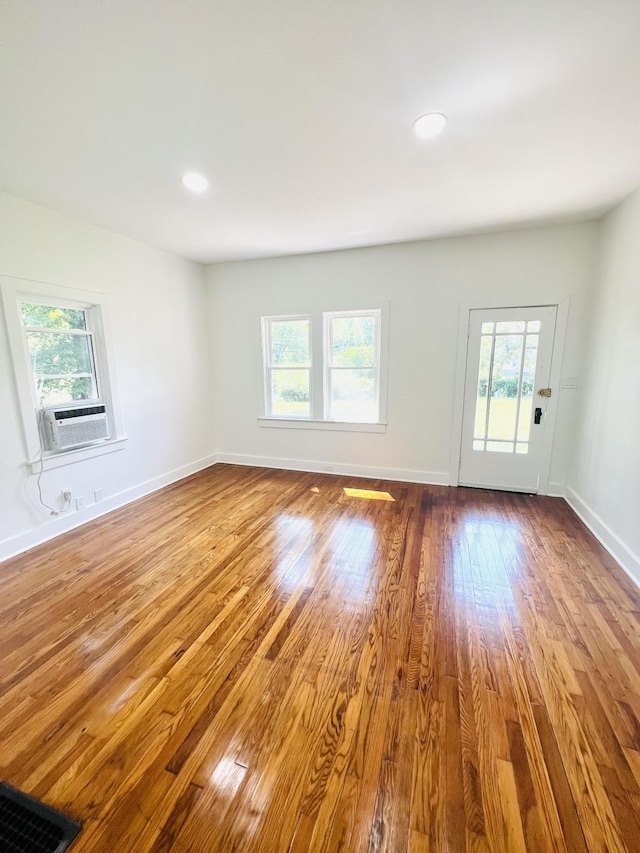 spare room with cooling unit, a wealth of natural light, and wood-type flooring